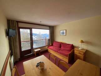 Enjoy stunning mountain views from this cozy living area, complete with a comfortable red sofa and a large window overlooking a scenic balcony.