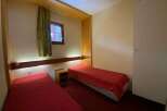 This cozy bedroom features two twin beds, each dressed in a vibrant red comforter, perfect for a comfortable stay.