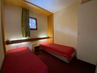 This cozy bedroom features two twin beds, each dressed in a vibrant red comforter, perfect for a comfortable stay.