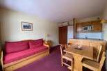 This charming studio apartment features a comfortable living area with a red sofa, perfect for relaxing after a day of skiing.