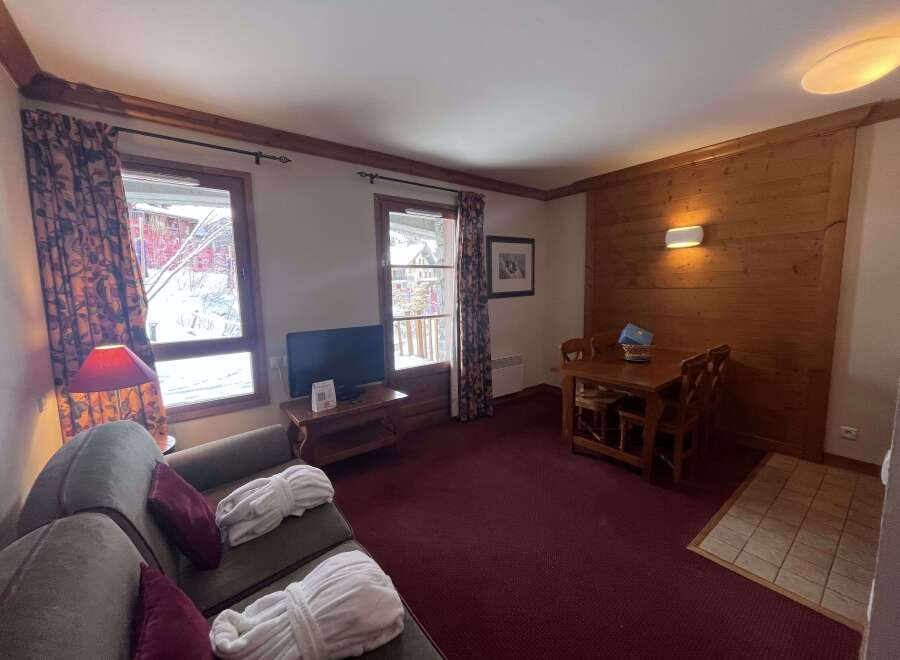 Experience cozy mountain living in this charming apartment, featuring a comfortable living area with plush seating and two plush bathrobes laid out for relaxation.