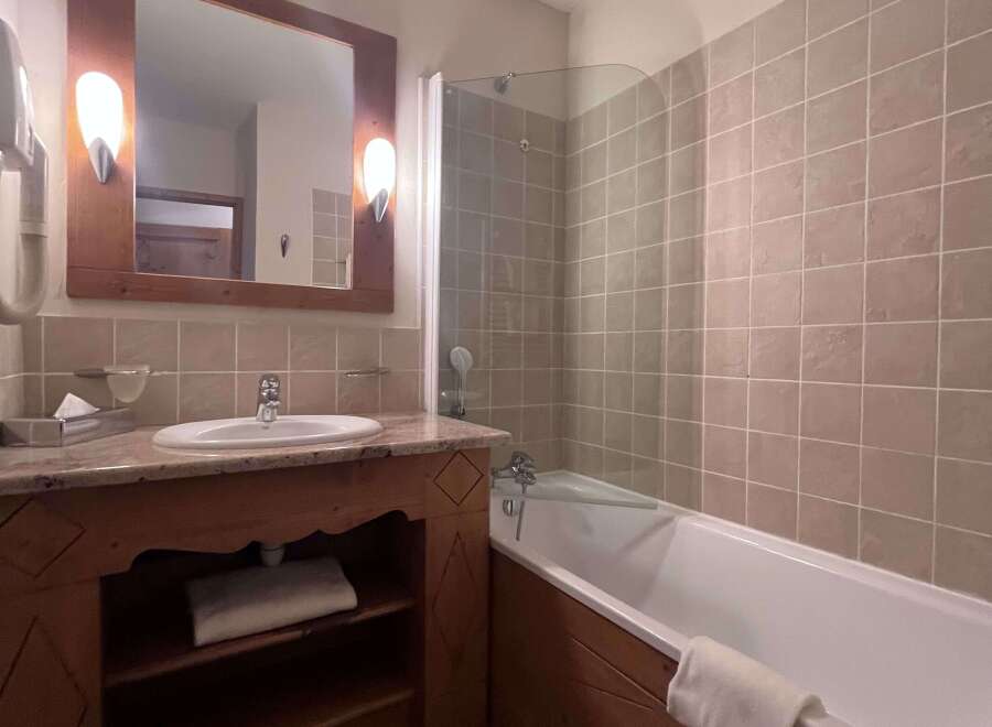 This charming bathroom features a spacious bathtub with a glass shower screen, perfect for relaxing after a long day.