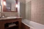 This charming bathroom features a spacious bathtub with a glass shower screen, perfect for relaxing after a long day.