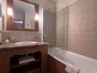 This charming bathroom features a spacious bathtub with a glass shower screen, perfect for relaxing after a long day.