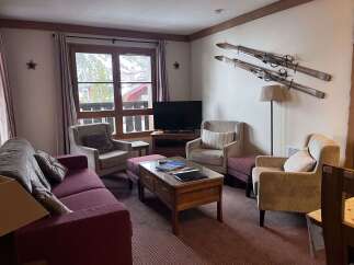 Experience cozy mountain living in this charming living room, featuring a plush sofa and comfortable armchairs perfect for relaxing after a day on the slopes.