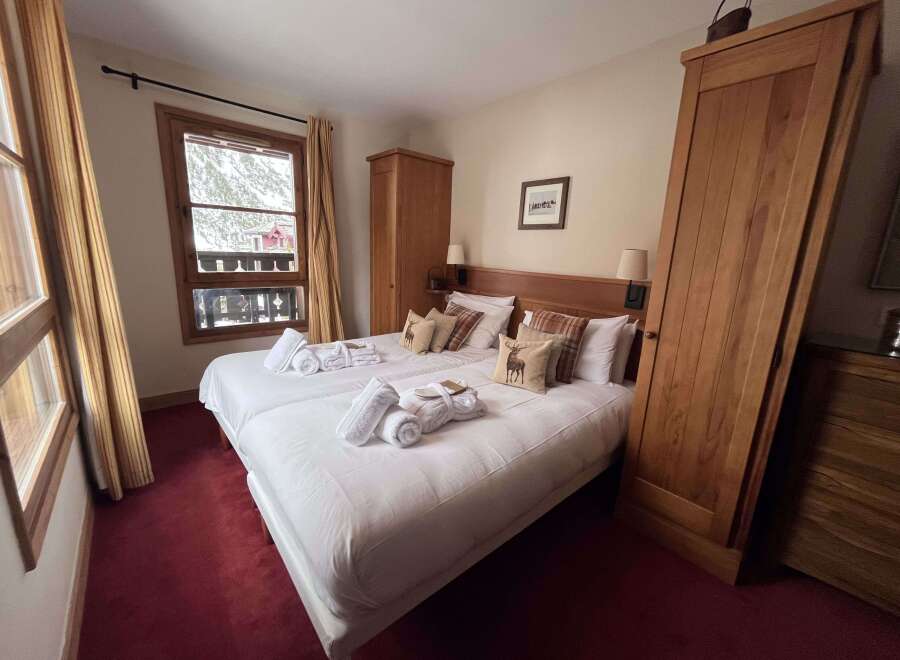 Experience cozy mountain living in this charming bedroom featuring two comfortable beds, perfect for a relaxing getaway.