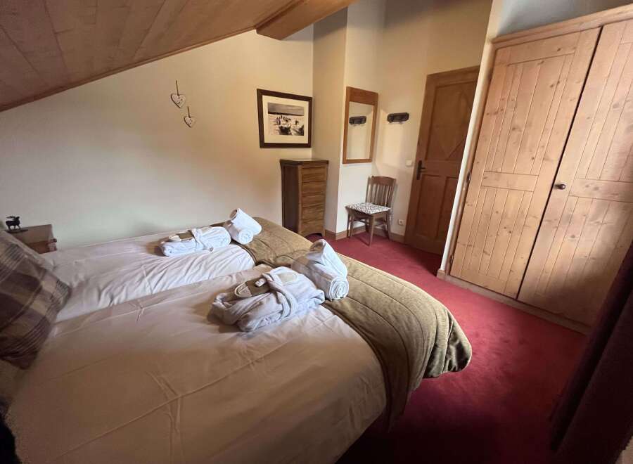 Experience ultimate comfort in this charming bedroom, featuring two cozy beds adorned with plush robes and rolled towels, ready for your relaxation.
