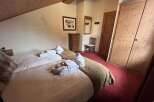 Experience ultimate comfort in this charming bedroom, featuring two cozy beds adorned with plush robes and rolled towels, ready for your relaxation.