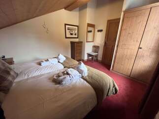 Experience ultimate comfort in this charming bedroom, featuring two cozy beds adorned with plush robes and rolled towels, ready for your relaxation.