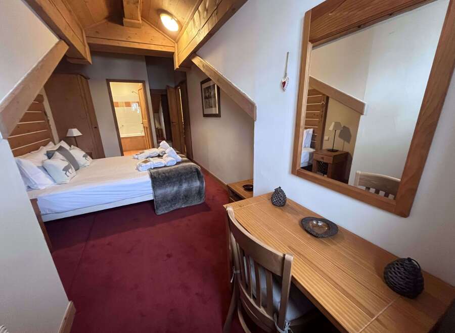 Experience cozy mountain living in this charming hotel room, featuring a comfortable bed adorned with decorative pillows and a plush throw.