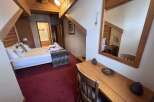 Experience cozy mountain living in this charming hotel room, featuring a comfortable bed adorned with decorative pillows and a plush throw.