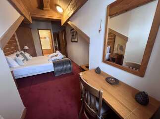 Experience cozy mountain living in this charming hotel room, featuring a comfortable bed adorned with decorative pillows and a plush throw.