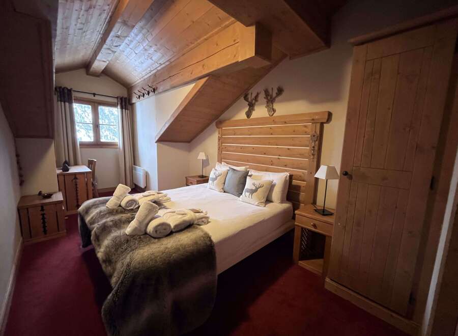 Experience rustic charm in this cozy mountain bedroom, featuring a comfortable bed adorned with plush throws and decorative pillows.