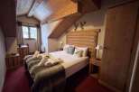 Experience rustic charm in this cozy mountain bedroom, featuring a comfortable bed adorned with plush throws and decorative pillows.