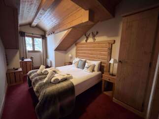 Experience rustic charm in this cozy mountain bedroom, featuring a comfortable bed adorned with plush throws and decorative pillows.