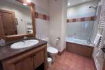 This charming bathroom features a spacious vanity with a granite countertop and ample storage, complemented by a large mirror with integrated lighting.