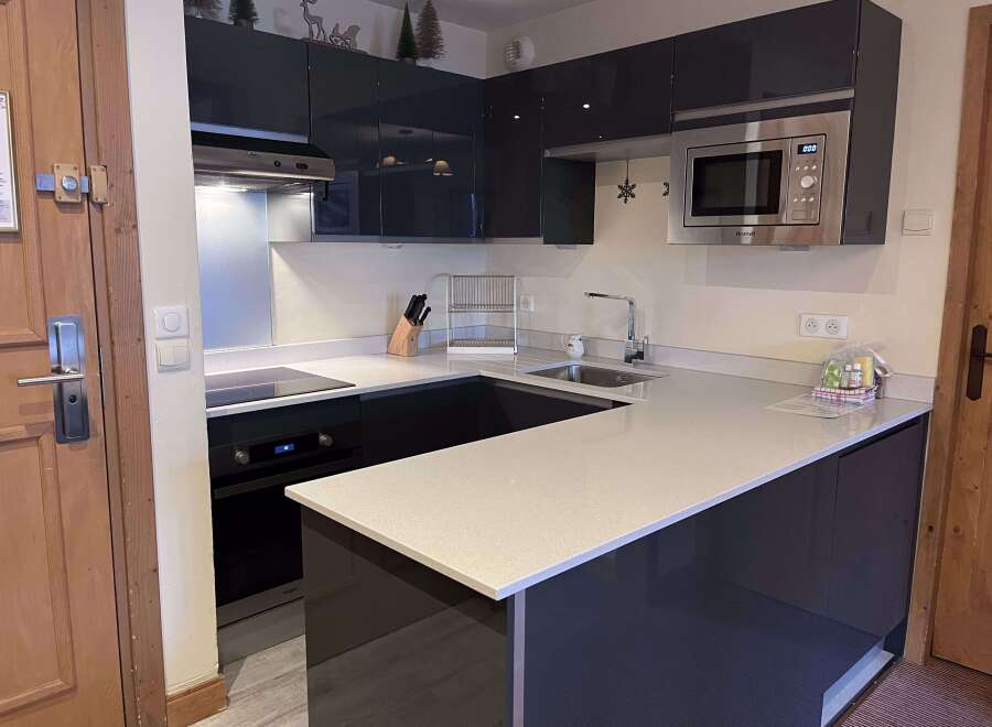 Experience modern living in this sleek kitchen featuring high-gloss dark cabinetry and a spacious quartz countertop.