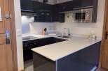 Experience modern living in this sleek kitchen featuring high-gloss dark cabinetry and a spacious quartz countertop.