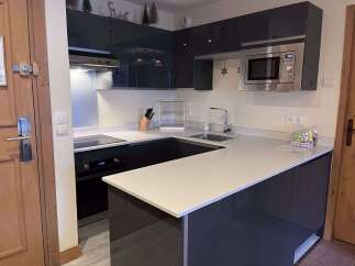 Experience modern living in this sleek kitchen featuring high-gloss dark cabinetry and a spacious quartz countertop.