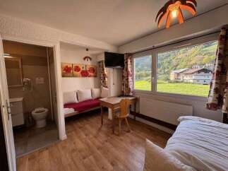 Experience breathtaking mountain views from this charming hotel room, featuring a comfortable seating area and a private bathroom.