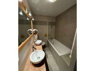 This modern bathroom features a sleek wooden vanity with two vessel sinks and contemporary faucets.