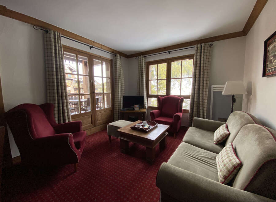 Experience cozy living in this charming living room, featuring plush red armchairs and a comfortable sofa perfect for relaxation.