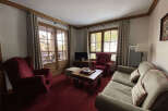 Experience cozy living in this charming living room, featuring plush red armchairs and a comfortable sofa perfect for relaxation.