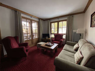 Experience cozy living in this charming living room, featuring plush red armchairs and a comfortable sofa perfect for relaxation.
