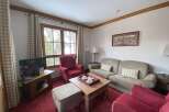 Experience cozy living in this charming living room, featuring a plush red armchair and a comfortable sofa perfect for relaxation.
