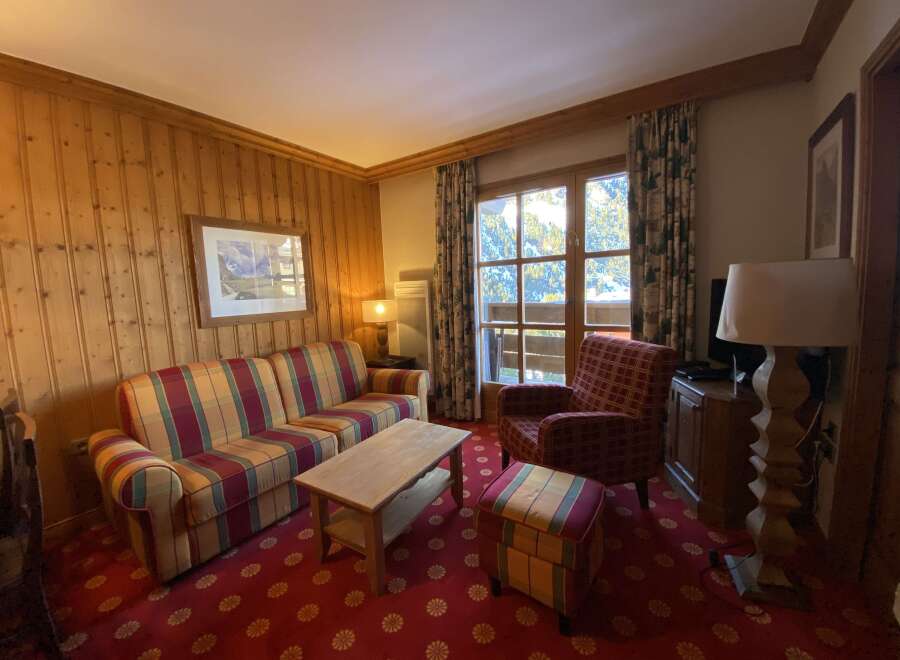 Experience cozy mountain living in this charming living room, featuring warm wood-paneled walls and a plush, striped sofa perfect for relaxing after a day on the slopes.
