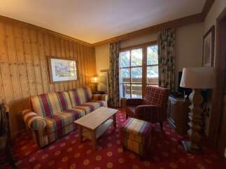 Experience cozy mountain living in this charming living room, featuring warm wood-paneled walls and a plush, striped sofa perfect for relaxing after a day on the slopes.