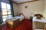 Experience cozy mountain living in this charming hotel room, featuring two comfortable twin beds perfect for solo travelers or friends.