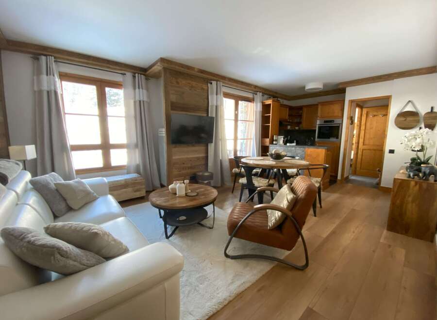 Experience cozy living in this charming apartment, featuring a spacious white leather sofa and a rustic wooden coffee table perfect for gatherings.