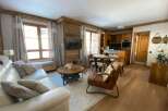Experience cozy living in this charming apartment, featuring a spacious white leather sofa and a rustic wooden coffee table perfect for gatherings.