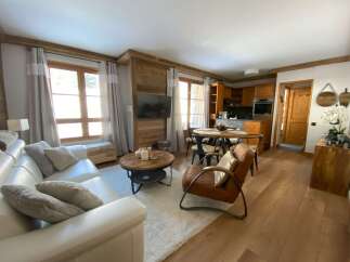 Experience cozy living in this charming apartment, featuring a spacious white leather sofa and a rustic wooden coffee table perfect for gatherings.