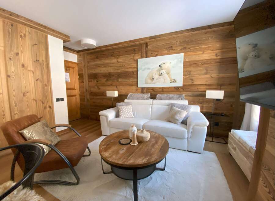 Experience rustic charm and modern comfort in this beautifully appointed living space, featuring warm wood paneling and a plush white sofa.