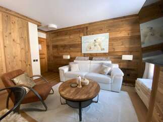 Experience rustic charm and modern comfort in this beautifully appointed living space, featuring warm wood paneling and a plush white sofa.