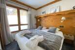 Experience ultimate comfort in this cozy bedroom, featuring a plush king-sized bed adorned with soft grey linens and two inviting bathrobes.