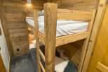 Experience cozy living in this charming room featuring rustic wooden walls and a sturdy bunk bed.