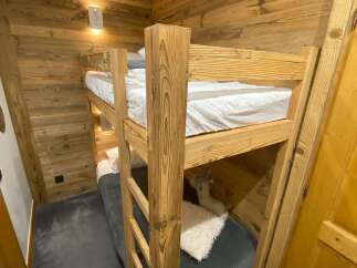 Experience cozy living in this charming room featuring rustic wooden walls and a sturdy bunk bed.