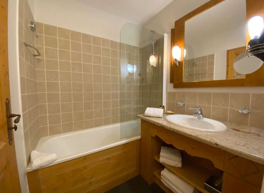 This charming bathroom features a spacious bathtub with a glass shower screen, perfect for relaxing after a long day.