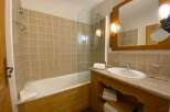 This charming bathroom features a spacious bathtub with a glass shower screen, perfect for relaxing after a long day.