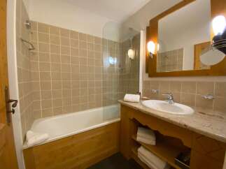 This charming bathroom features a spacious bathtub with a glass shower screen, perfect for relaxing after a long day.