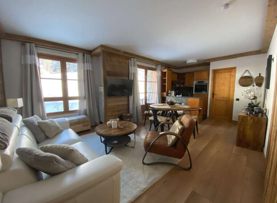 Experience cozy living in this charming mountain retreat, featuring a spacious white leather sofa and a rustic wooden coffee table.