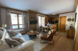 Experience cozy living in this charming mountain retreat, featuring a spacious white leather sofa and a rustic wooden coffee table.