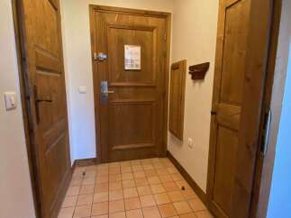 Step into a warm and inviting entryway featuring rustic wooden doors and trim, complemented by classic terracotta tile flooring.