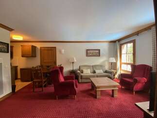 Experience cozy living in this charming living room, featuring plush red armchairs and a comfortable sofa perfect for relaxation.