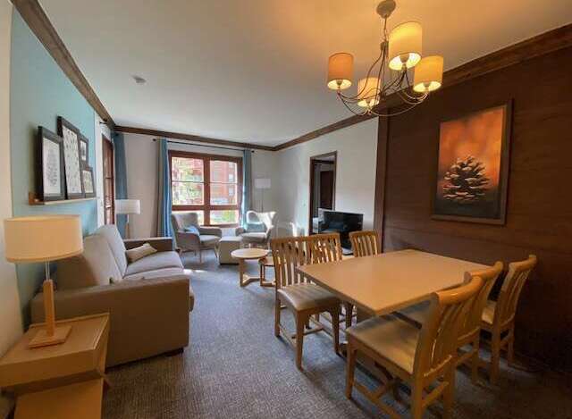 This inviting living and dining area features a comfortable sofa, a stylish chandelier, and a spacious dining table perfect for family meals.