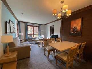 This inviting living and dining area features a comfortable sofa, a stylish chandelier, and a spacious dining table perfect for family meals.
