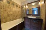 This charming bathroom features a spacious bathtub with a grab bar, perfect for a relaxing soak.